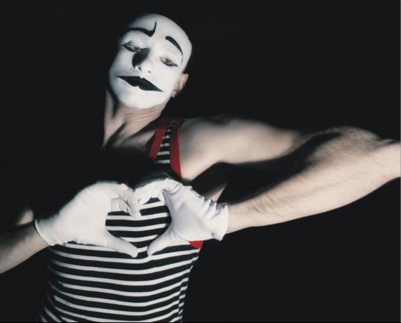 Pantomime formt mit weißen Handschuhen ein Herz